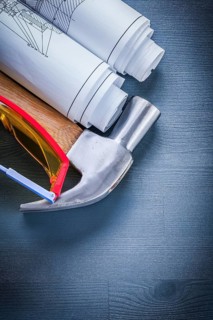 Vertical view rolled up blueprints hammer goggles