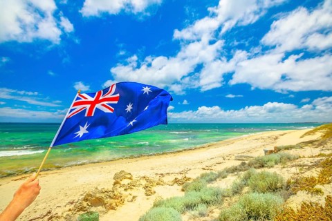 Australian flag waving on the foreground with coastal landscape of Mettams Pool, Trigg Beach, North