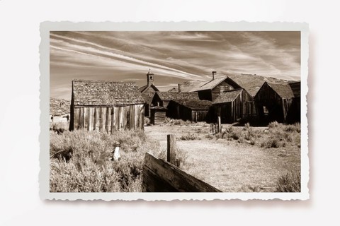 A dusty path between thorny undergrowth leads to wooden houses in the former gold mining town of