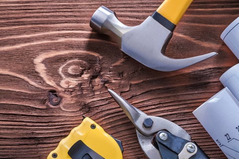 Claw hammer blueprints nippers and tape-measure on wood board construction concept