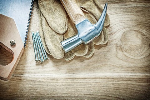 Set of claw hammer safety gloves handsaw nails on wooden board construction concept