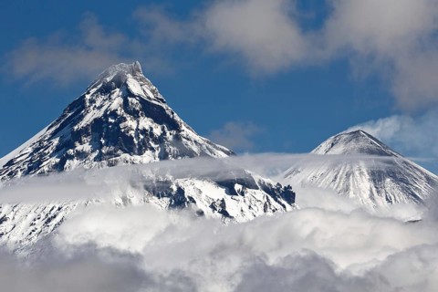 Stunning landscape view of snowy top of rocky volcanoes cones of Kamen Volcano and active