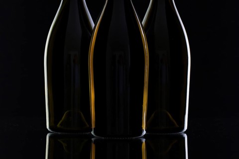 Three different bottles of wine on the black glass