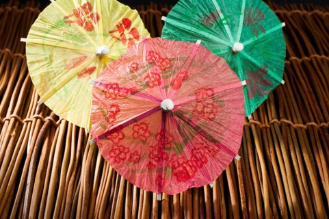 Colorful cocktail umbrellas on wooden base. Close up