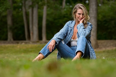 A beautiful blonde model enjoys the late summer sun outdoors. Surrounded by lush greenery and soft