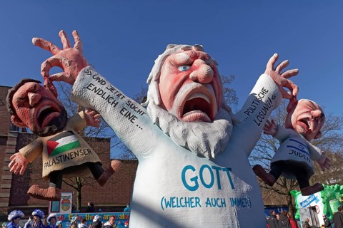 God figure grabs an Israeli and a Palestinian by the ear, themed float on the Gaza War by Jacques
