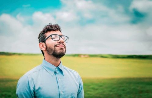 Relaxed young man breathing fresh air in the field. Serene man breathing fresh air in the field