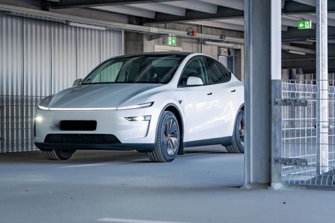 White electric car with modern lines and LED lights in a multi-storey car park, Tesla New Model Y