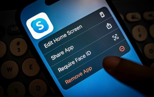 In this photo illustration, a person holds a mobile phone displaying Skype application, in