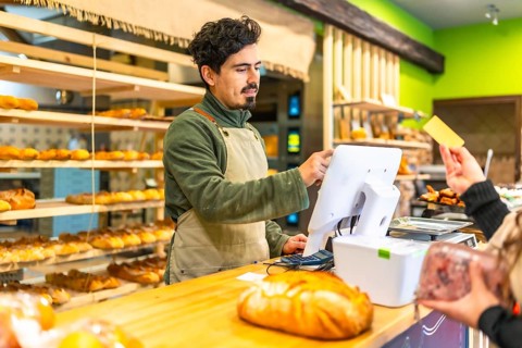 Woman waiting to check out and pay with credit card in an artisan bakery