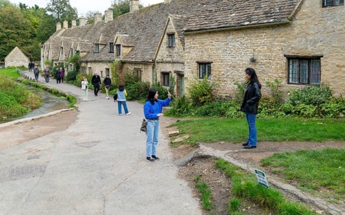 Tourists visiting famous Cotswold buildings at Arlington Row, Bibury, Gloucestershire, England, UK