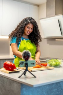 Vertical photo of a latin young female influencer recording a health food tutorial at home