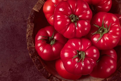 Pink tomatoes, in a rustic wooden bowl, close-up, no people
