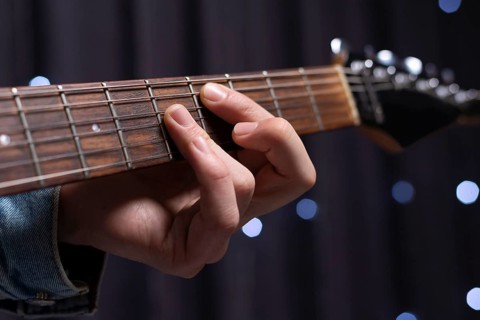 Image of the hands of a musician playing the electric guitar. The concept of concerts and