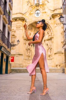 Beautiful Dominican ethnic girl with braids with a beautiful pink dress. Fashion enjoying summer in