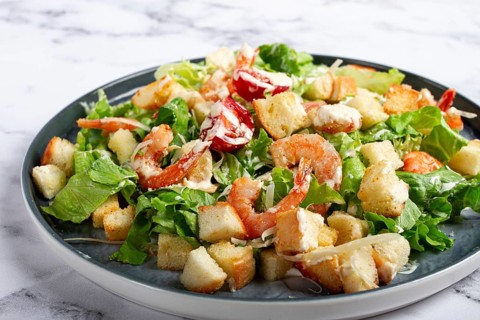 Caesar salad, with shrimp, on a marble background, top view, no people
