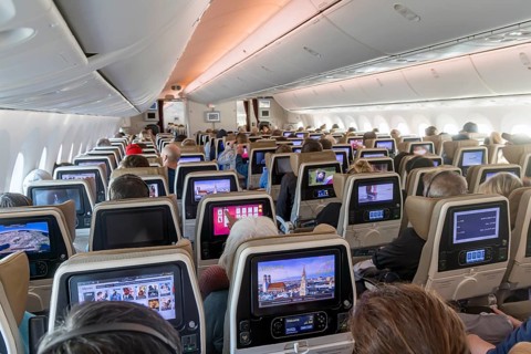 Etihad airline aircraft, interior, rows of seats with passengers. Boeing 787 aircraft on a flight