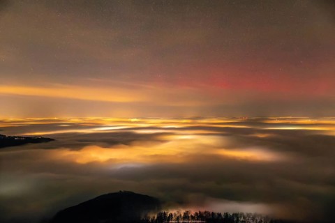 Firework lights under the sea of fog. New Year's Eve fireworks 2024 and a little red Aurora