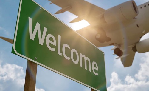 Welcome green road sign with airplane above