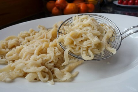 Swabian cuisine, preparation of spaetzle, hand-scraped spaetzle, on serving platter, slotted spoon,