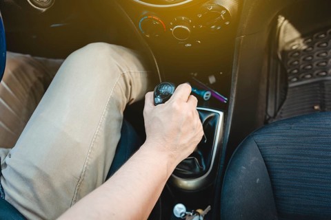 Driver hand grabbing car gear stick, closeup of hands accelerating on gear stick. Close-up of