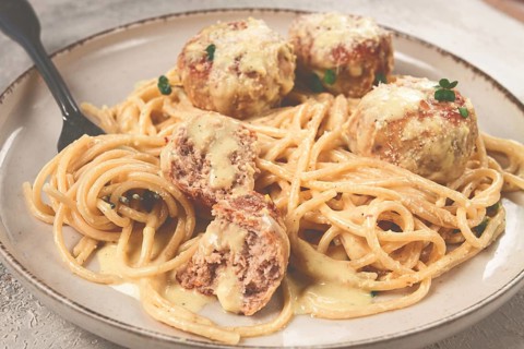 Spaghetti with chicken meatballs, with cream sauce, and parmesan cheese, and decorated with