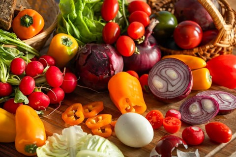 A variety of vegetables, including peppers and tomatoes, with a boiled egg and lettuce leaves