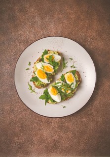 Sandwich with mashed avocado, boiled egg, and arugula, on bread, homemade, breakfast
