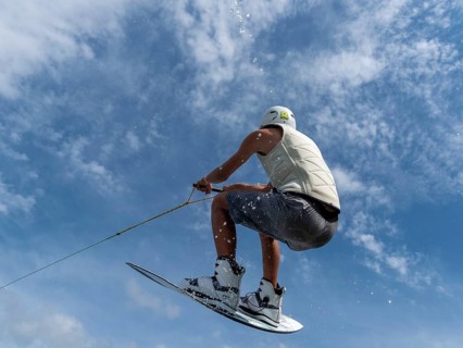 Young man jumping and flying with wakeboard, water sports and water skiing in the wakepark