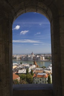 Budapest city skyline with Danube river and Hungarian parliament through stone arch in summer,