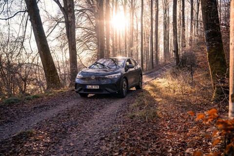 Vehicle on a forest path, illuminated by sunlight through the trees, car sharing, electric car,