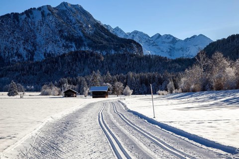 Winter landscape in the snow, cross-country skiing trail through snowy landscape, behind mountains