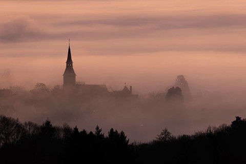 Wisps of mist drift into the town of Kronberg im Taunus in the morning shortly in front of sunrise.