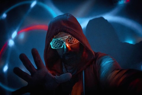 Cyberpunk man with glowing glasses uses augmented reality in futuristic technological environment