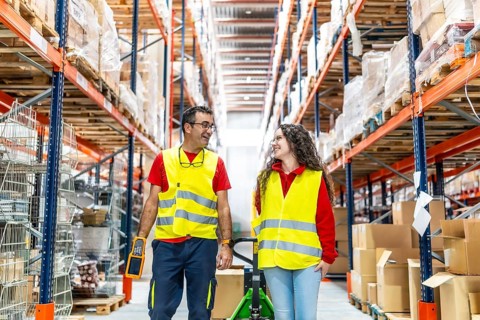 Frontal view of a mature male and young female workers of warehouse walking and chatting while