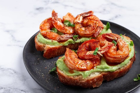 Sandwiches with avocado and caramelized shrimp, micro-greens, breakfast, on a plate, top view,