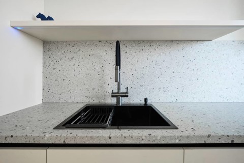 A sleek kitchen showcases a contemporary sink with a black finish, set against a light speckled