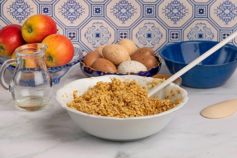 Oatmeal porridge with eggs and apples in a bowl on a marble worktop in front of patterned tiles
