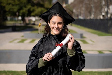 Woman recent graduated, dressed in cap and gown, showing off his degree celebrating