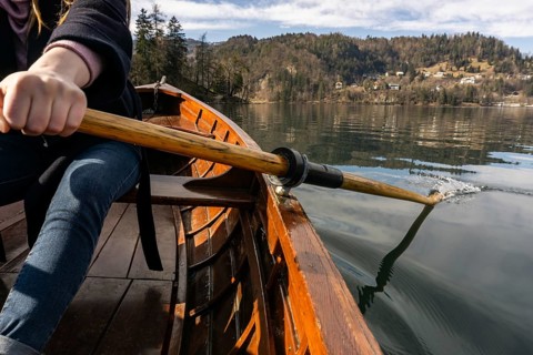 Young woman using paddle on a wooden boat, Lake Bled Slovenia rowing on wooden boats on a sunny day