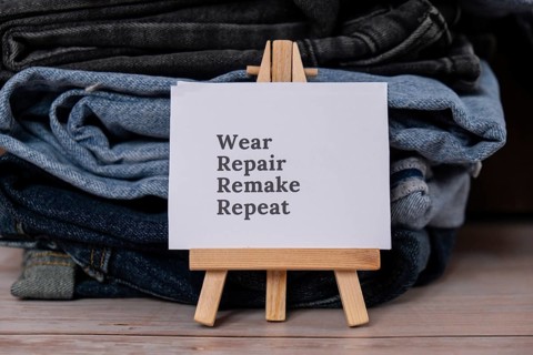 WEAR REPAIR REMAKE REPEAT text on paper note on Jeans clothes assortment Second hand sustainable
