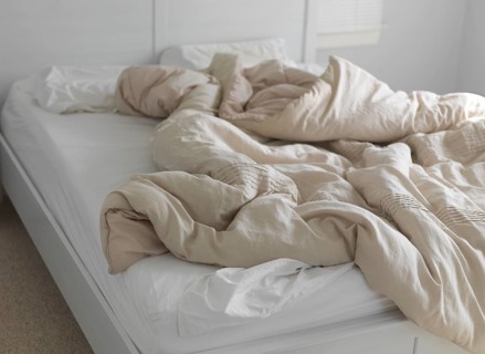 Unmade bed with ruffled blanket