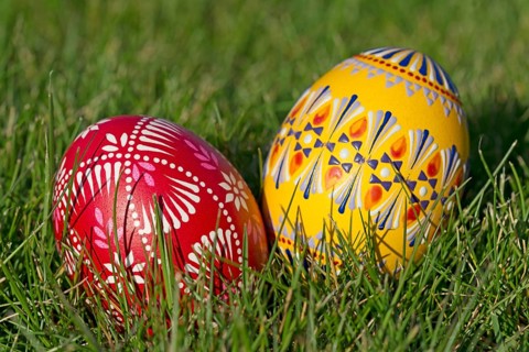 Two traditionally hand-painted Easter eggs lie in the grass