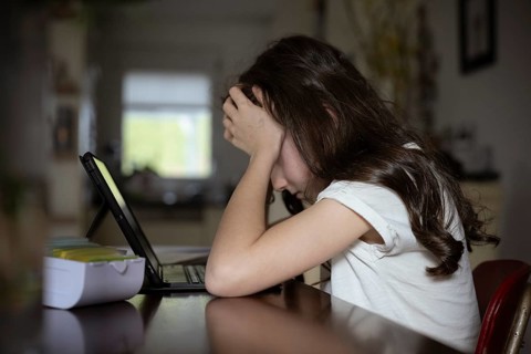 Girl, 10 years old, sits at the table with a tablet and learns