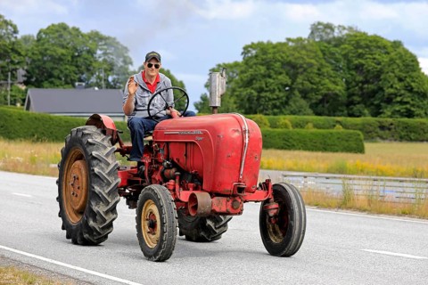 Kimito, Finland. July 6, 2019. Young man greets as he drives classic Porsche-Diesel Super Tractor