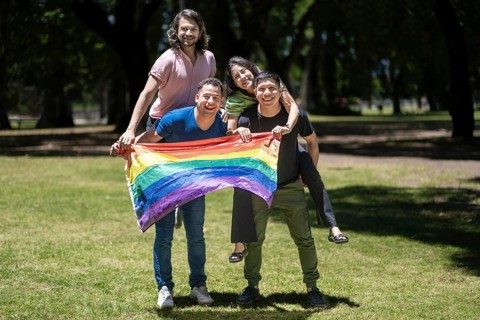 Group of latin friends holding the LGBT flag
