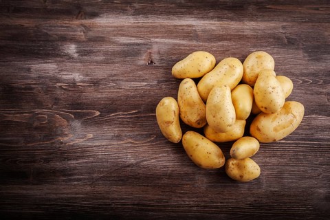 Fresh organic potatoes on a wooden table with copy space