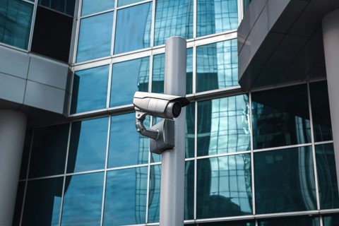 External surveillance camera against glass building facade