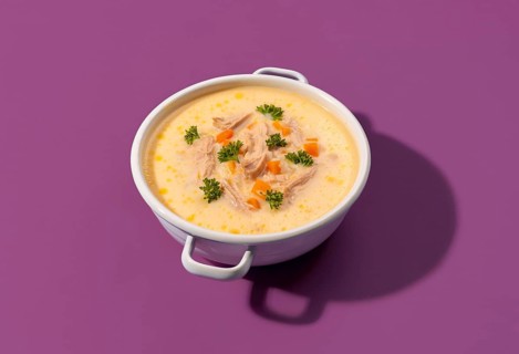 Delicious greek chicken soup with lemon juice and vegetables, in a white enamel bowl, isolated on a