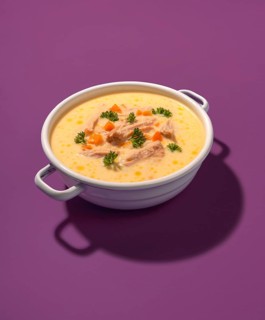 Traditional greek chicken soup in a white enamel bowl, isolated on a purple background